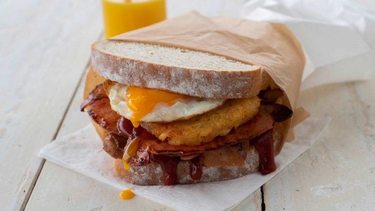Image of a tradie sandwich that has bacon, sausage, egg and hash brown