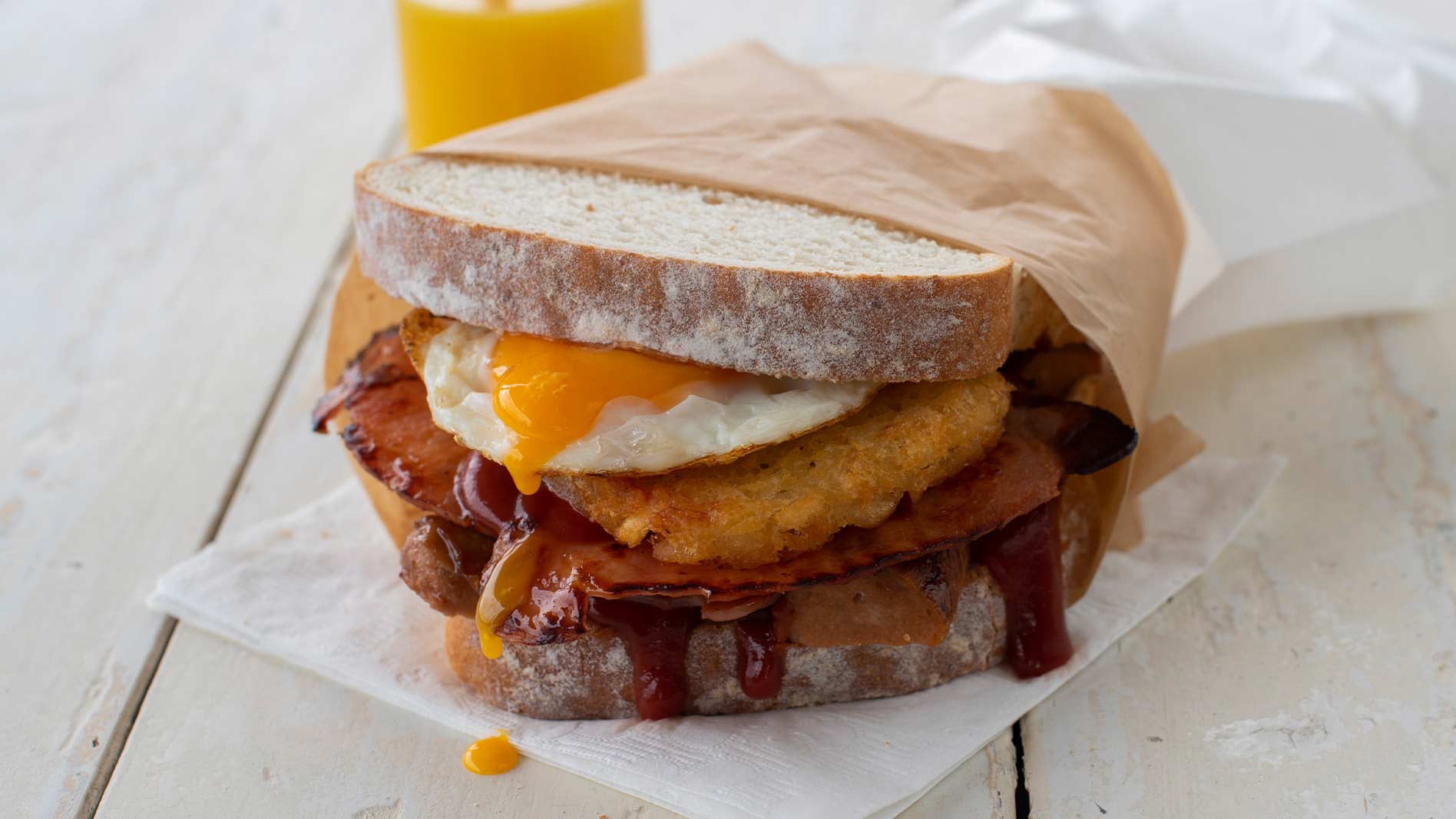 Image of a tradie sandwich that has bacon, sausage, egg and hash brown